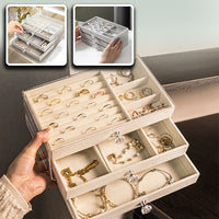 Boite a bijoux transparente design remplie de beaux bijoux porté par une main